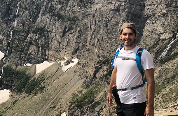 man wearing backpack standing on a mountain overlook